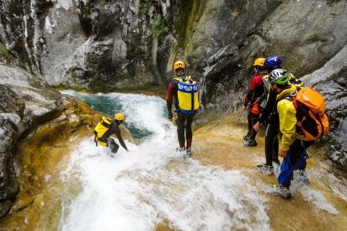 Guida alpina mostra come affrontare una discesa di canyoning su uno scivolo naturale toboga in Valtellina