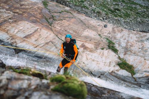 Guida alpina mostra come fare una calata con la corda durante un canyoning in Valchiavenna