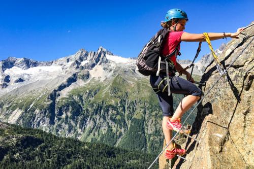 Ragazza percorre via ferrata sotto le indicazioni della guida alpina in Valmalenco