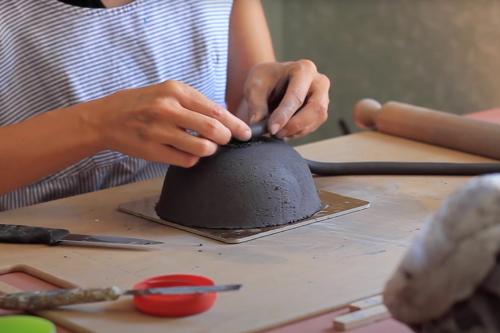 Ceramista manipola l'argilla con la tecnica a colombino durante l'esperienza di ceramica in un laboratorio in Valchiavenna in Lombardia