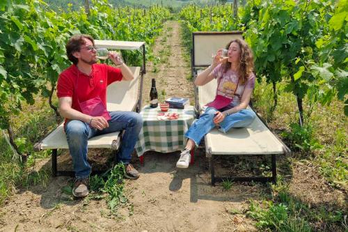 Due ragazzi degustano dei calici di vino bianco tra i filari di una cantina biologica in Oltrepò Pavese