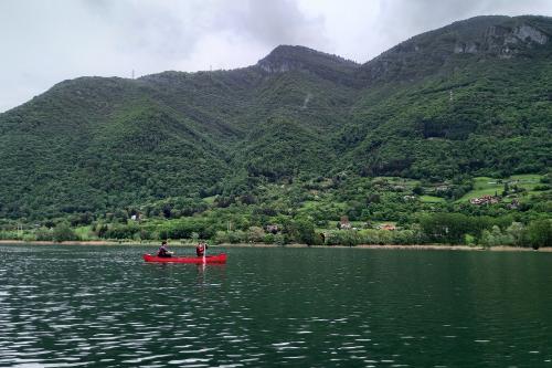 Due ragazzi pagaiano a bordo di una canoa canadese rossa sul fiume Adda in Lombardia sullo sfondo le montagne