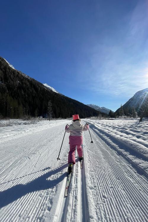 Bambina con tuta rosa e bianca che fa sci di fondo nella piana del Gaver vicino a Brescia