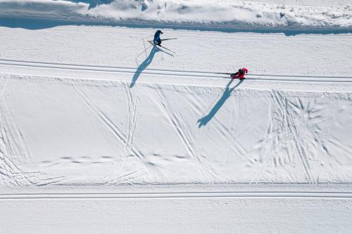 Due persone che fanno sci di fondo su una pista innevata vista dall'alto