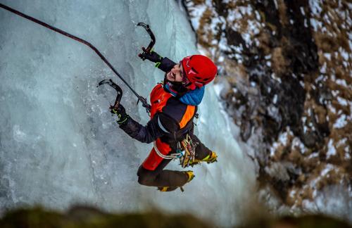 Un ragazzo sta scalando delle rocce ghiacciate  durante un corso di ice climbing in Valtellina