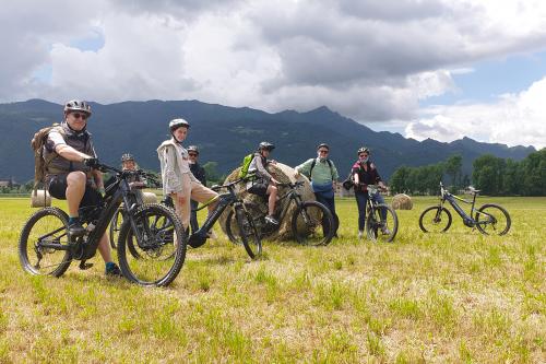 Un gruppo di persone ferme in posa in sella a delle bici in un campo vicino delle balle di fieno