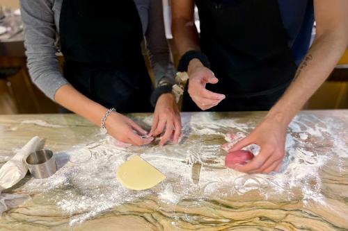 Due giovani ragazzi durante un corso di cucina per coppie si divertono a preparare ravioli ripieni mentre indossano delle manette