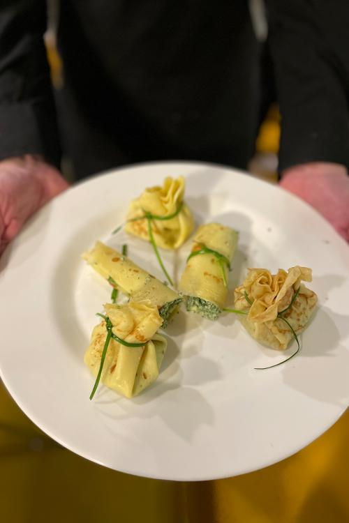 Un signore tiene in mano un piatto con gli involtini che ha appena preparato durante il corso di cucina a Milano