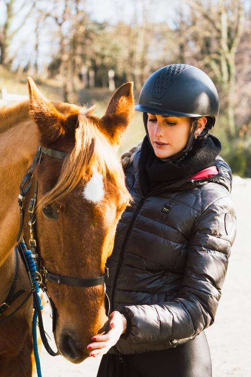 Una ragazza sta accarezzando il muso di un cavallo arabo marrone