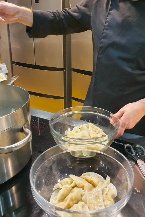 Lo chef durante il corso di cucina mostra come cuocere la pasta ripiena fresca dopo la sua preparazione