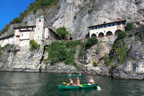 Sul Lago Maggiore delle ragazze stanno facendo un tour guidato a bordo di canoe canadesi vicino Santa Caterina del Sasso