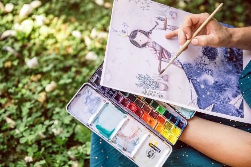 Una ragazza durante un workshop en plein air di acquerello nel Parco Pineta in Lombardia mentre realizza una illustrazione