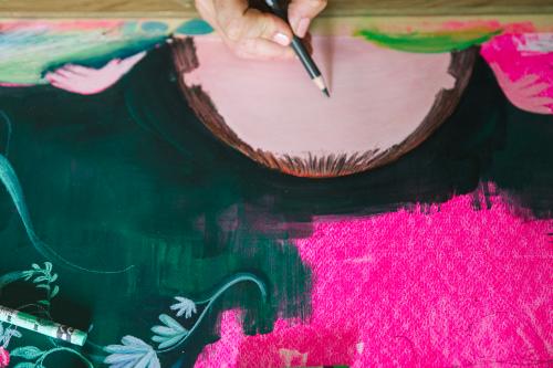 Una ragazza che disegna dei particolari con una matita verde su un foglio ricco di colori durante il corso di illustrazione vicino Como
