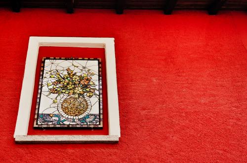 Parete rossa nel centro storico di Brenta vicino a Varese in Lombardia sulla quale è stato posizionato un mosaico che rappresenta un vaso di fiori