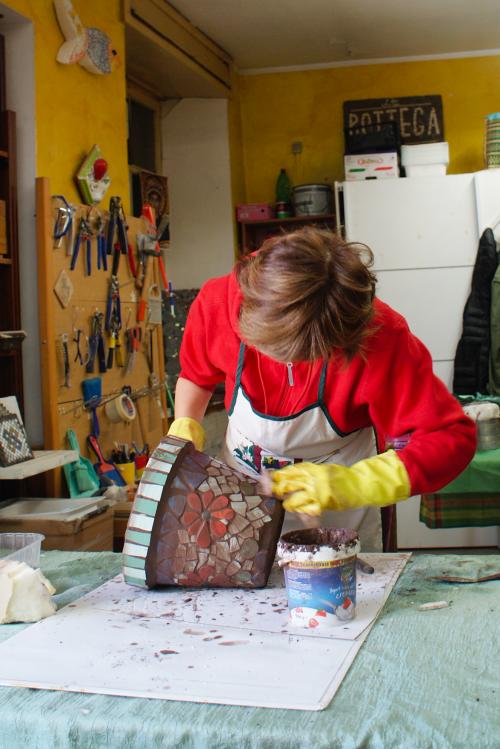 Una signora in un laboratorio artistico vicino al Lago Maggiore in Lombardia è intenta a fare un mosaico su di un vaso