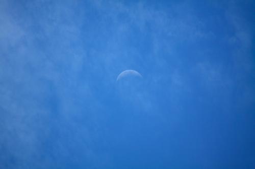 La luna che inizia a comparire nel cielo azzurro blu dopo che il sole è tramontato in Lombardia