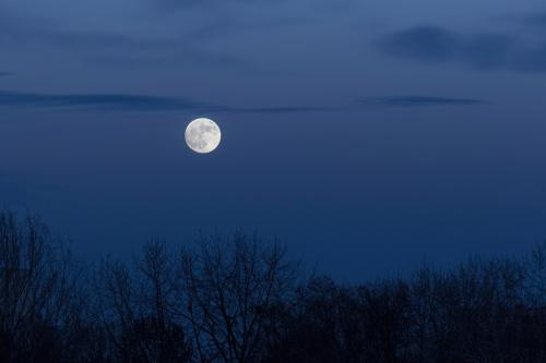Luna piena bianca e luminosa nel cielo blu azzurro della tarda sera in Lombardia