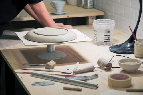 Una ragazza mentre manipola l'argilla per creare un set di piatti per colazione durante il workshop di ceramica a Brescia