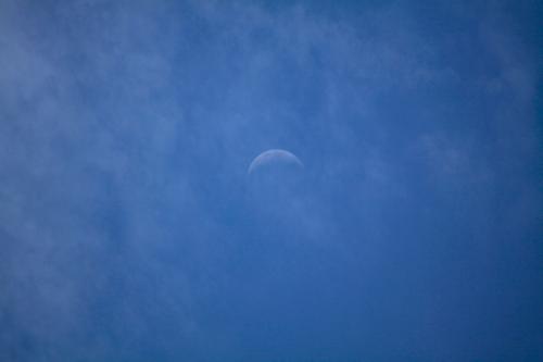 La luna che inizia a comparire nel cielo azzurro blu dopo che il sole è tramontato in Lombardia