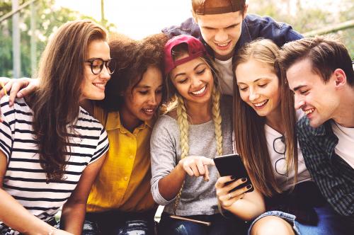Un gruppo di ragazzi mentre leggono su uno smartphone le indicazioni per svolgere un escape game urbano nel centro storico di Pavia in Lombardia