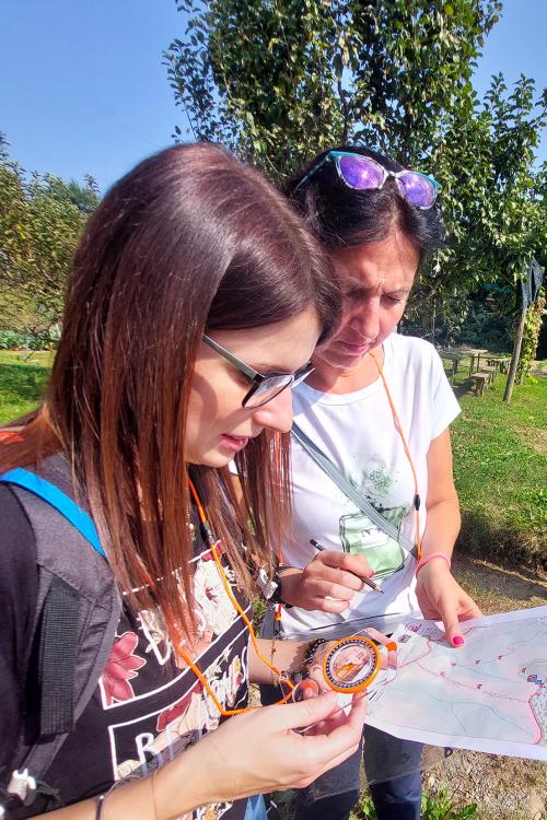 Due ragazze munite di bussola e mappa stanno partecipando all'esperienza di orienteering vicino al Lago di Garda in Lombardia