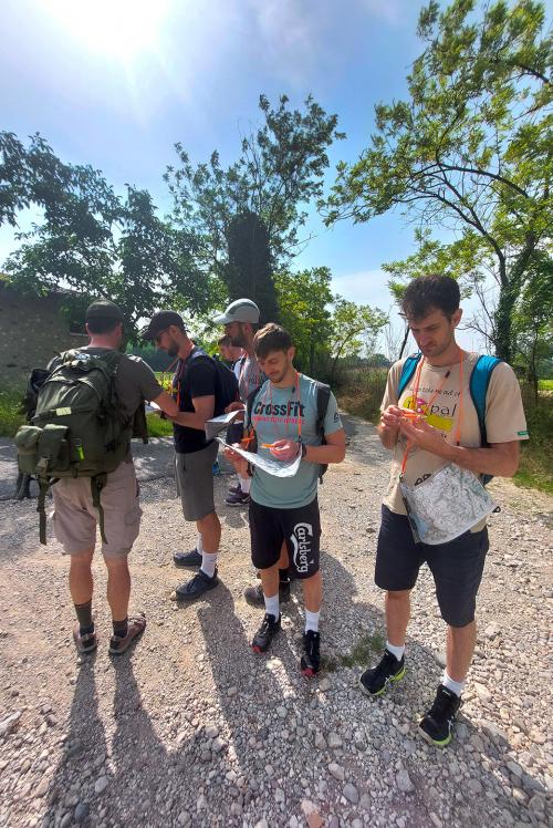 Un gruppo di ragazzi attrezzati con mappe e bussole sta partecipando ad una esperienza di orienteering in Lombardia
