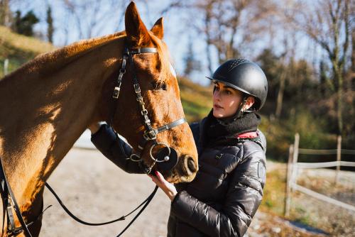 Una ragazza prende confidenza con il suo cavallo prima di montare in sella