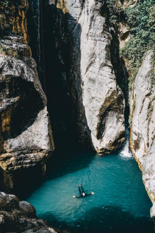 Un ragazzo in una vasca d'acqua ai piedi di una cascata lungo il torrente Campione in Lombardia vicino al Lago di Garda durante una esperienza di canyoning