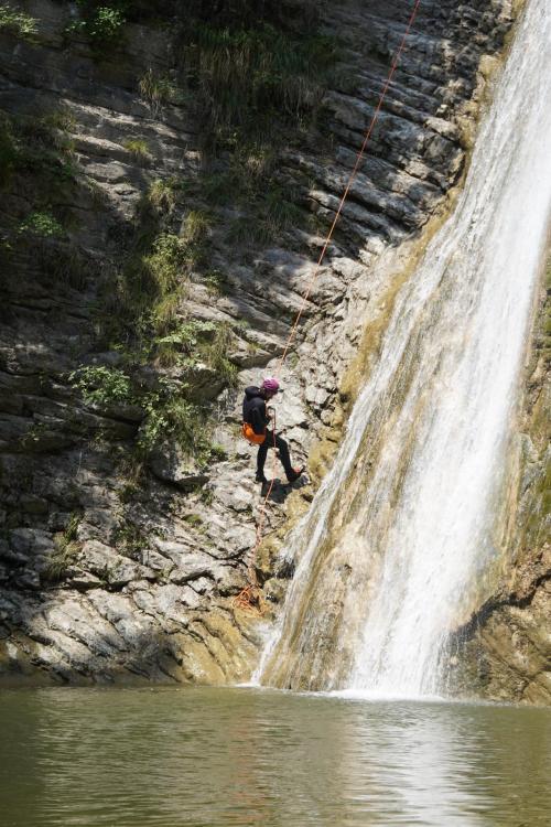 Un ragazzo durante una esperienza di canyoning in Lombardia vicino al Lago di Garda si sta calando con una corda sulle rocce vicino alla cascata