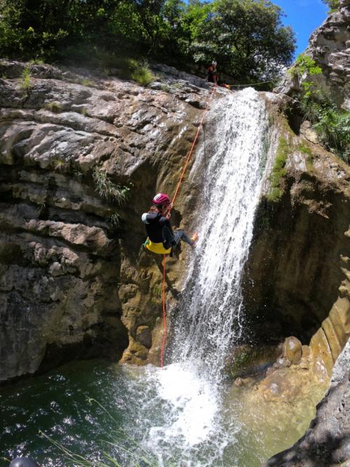 Una ragazza si cala da una cascata sul torrente Vione durante una esperienza di canyoning in Lombardia