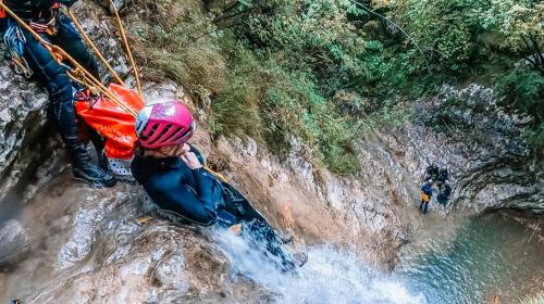 Una ragazza si cala da una cascata sul torrente Vione durante una esperienza di canyoning in Lombardia