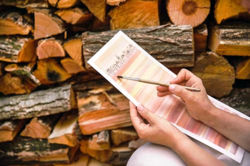 Mani di una ragazza che dipinge en plein air con gli acquerelli durante un workshop nel bosco in Lombardia sullo sfondo una catasta di legna