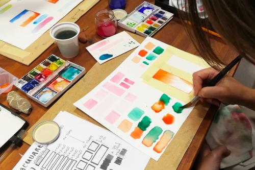 Una ragazza con il pennello in mano sta dipingendo con gli acquerelli durante un corso creativo in Lombardia vicino a Como