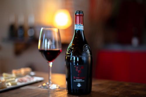 Una atmosfera calda e accogliente sul tavolo degli assaggi di prodotti del territorio una bottiglia e un calice di vino rosso durante una degustazione in Oltrepò Pavese in Lombardia
