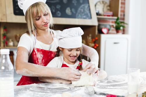 Mamma e figlia durante una cooking class a Milano in Lombardia insieme manipolano l'impasto per fare dei biscotti