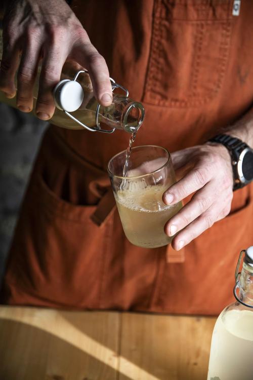 Lo chef mentre versa la bevanda fermentata durante il corso di kombucha con degustazione sul Lago di Como in Lombardia