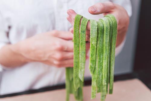 Una ragazza tiene in mano delle tagliatelle di pasta fresca fatta artigianalmente durante il laboratorio di cucina sul Lago di Como in Lombardia
