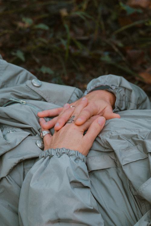 Una donna sdraiata nell'erba medita e si rilassa durante una esperienza di forest bathing nella valle del Curone in Lombardia