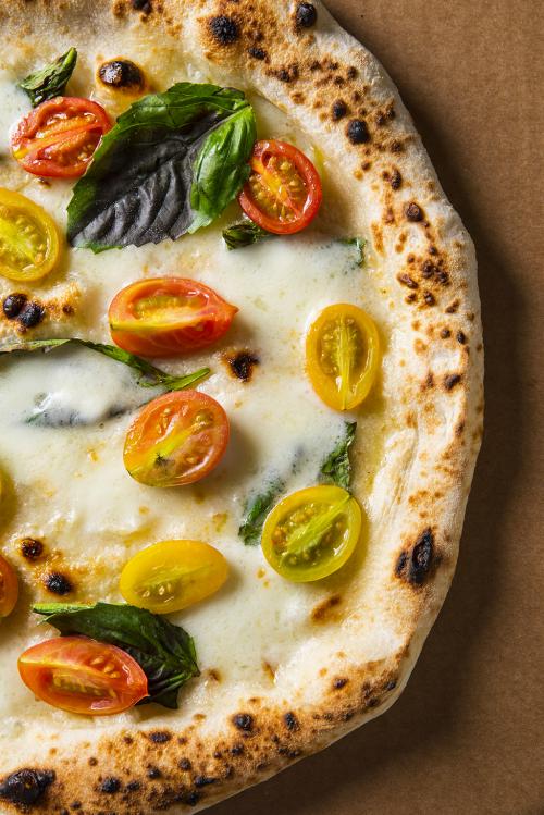 Pizza con pomodorini gialli e rossi e formaggio sciolto preparata durante il corso sui lievitati a Milano in Lombardia