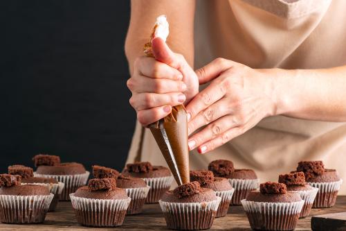 Durante il corso base di pasticceria a Milano in Lombardia una ragazza riempie dei muffin al cioccolato