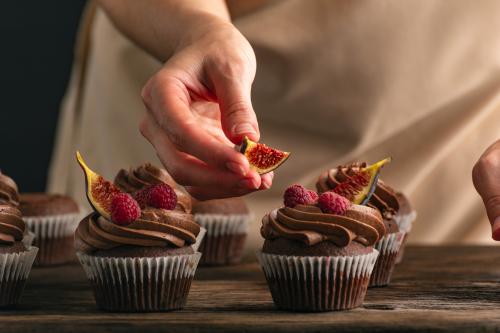 Una ragazza decora dei muffin al cioccolato con fichi e lamponi durante il corso di pasticceria a Milano in Lombardia