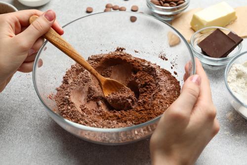 Mani di una ragazza mentre mescola gli ingredienti per fare un dolce al cioccolato durante il corso base di pasticceria a Milano in Lombardia