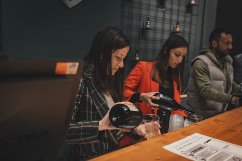 Dei ragazzi stanno versando nei bicchieri delle birre agricole presso un birrificio a nord del Lago d'Iseo in Lombardia