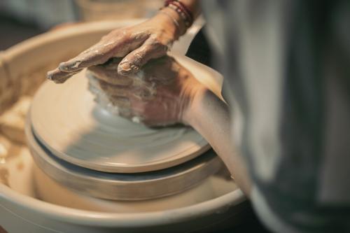 Mani di una ragazza mentre impara a realizzare dei bicchieri con il tornio durante il corso di ceramica in Valchiavenna in Lombardia
