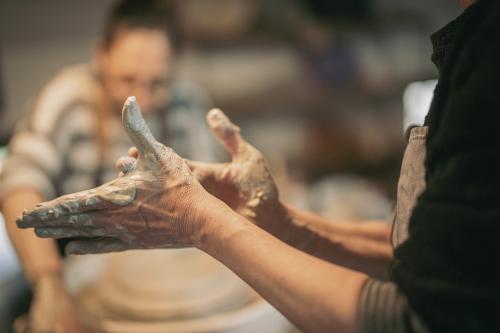 Mani di una ragazza sporche di argilla dopo che ha realizzato dei bicchieri con il tornio durante il corso in Valchiavenna in Lombardia