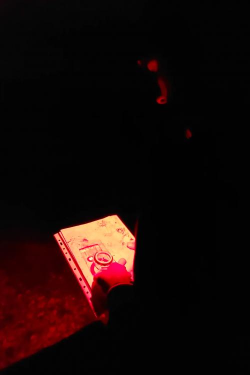 Durante il corso di orienteering notturno a Manerba del Garda in Lombardia un ragazzo utilizza bussola e mappa per orientarsi