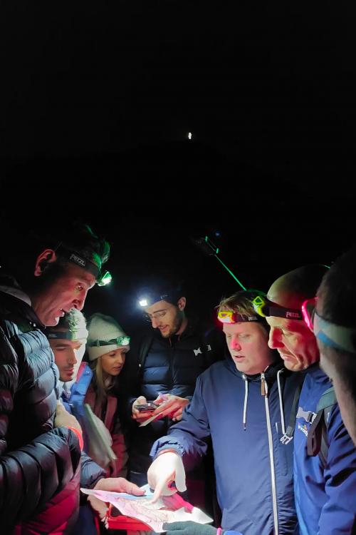 Un gruppo di ragazzi impara ad usare mappa e bussola per orientarsi nella notte in un' area boschiva vicino al Lago di Garda in Lombardia