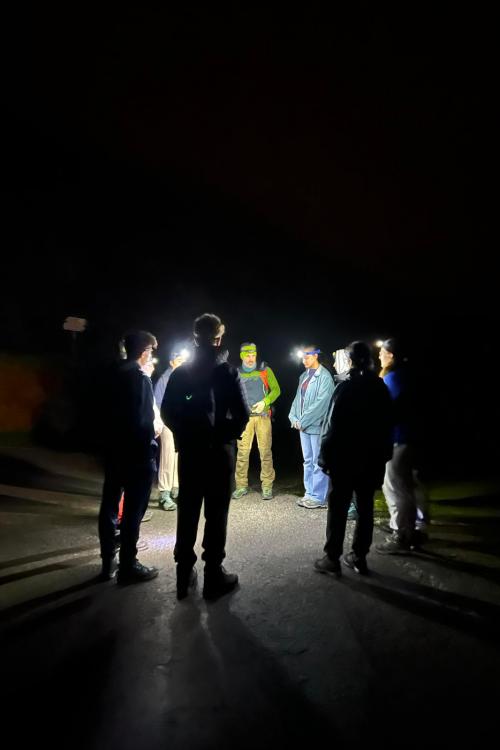 Un gruppo di persone imparano grazie al supporto di una guida ad orientarsi in un bosco al buio durante il corso di orienteering sul Lago di Garda in Lombardia