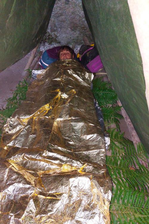 Una ragazza dorme sotto un riparo autocostruito durante il corso di survival vicino a Bergamo