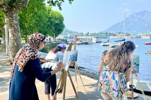 Delle ragazze in riva al Lago di Como partecipano al corso di pittura en plein air in Lombardia